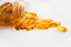 Fish oil capsules spilling out of a pot on it's side on a white table