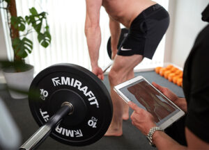 patient lifts weights as practitioner studies with aid of a digital tablet device