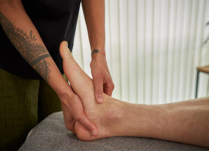 patient's foot receiving gentle reflexology treatment from a practitioner